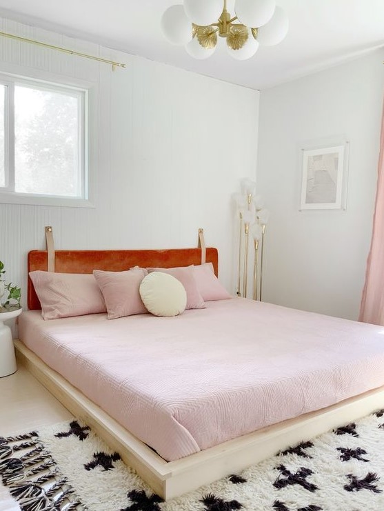 a welcoming girlish bedroom with pink bedding and an amber leather headboard hanging