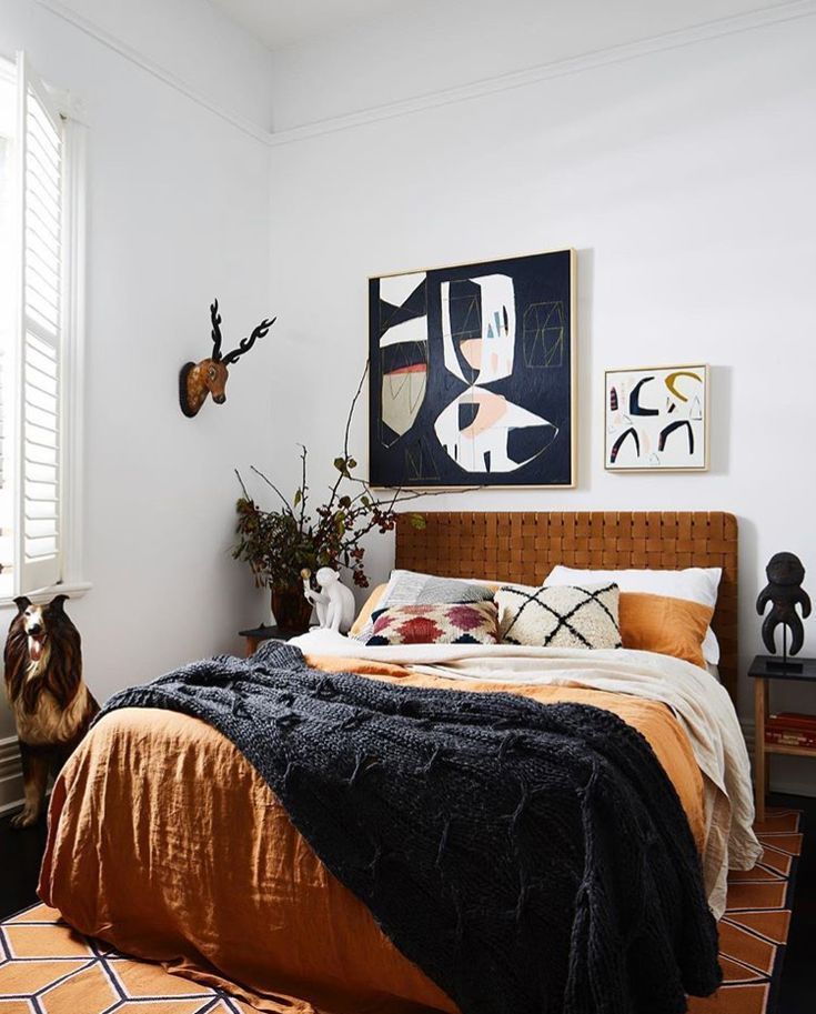 a whimsical bedroom with a bed and a leather woven headboard, bright bedding, faux taxidermay and bold artwork