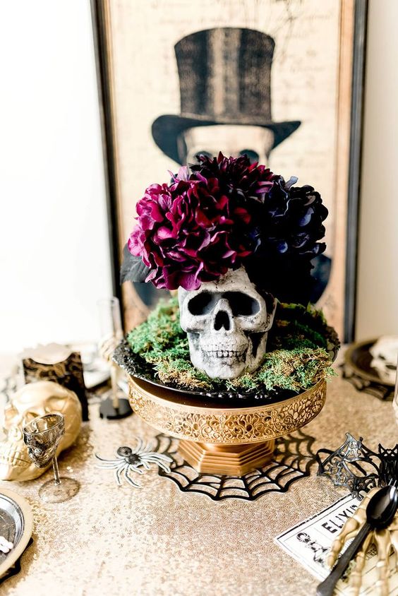 an exquisite Halloween centerpiece of a gold bowl, hay, a skull with dark blooms and leaves is a cool idea