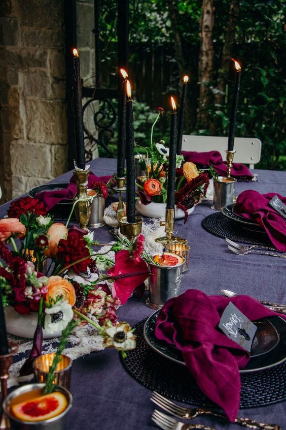 bold Halloween table styling with bright blooms, black candles in gold candleholders and bold napkins