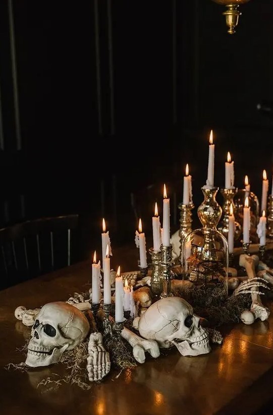 creepy and chic Halloween decor of skulls, bones, moss and candles in refined vintage candlesticks looks stylish and very elegant