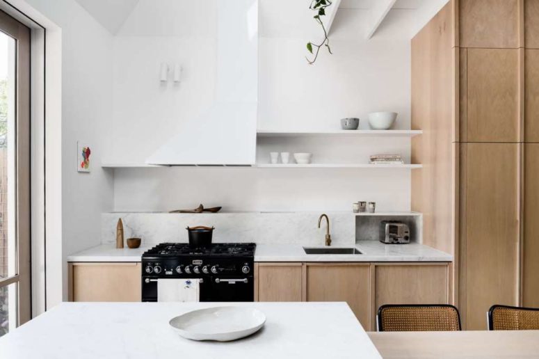 The kitchen is done in neutrals, with sleek plywood cabinets and white marble