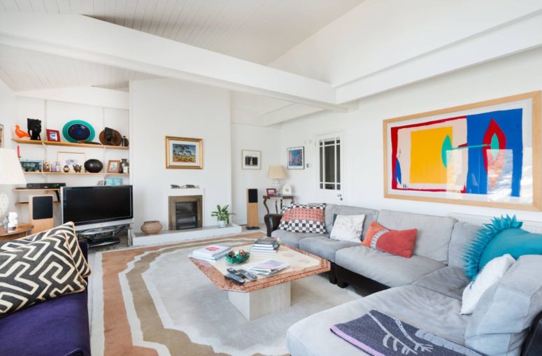 this basically neutral living room was spruced up with bright artworks, rugs, pillows for a bold and chic look