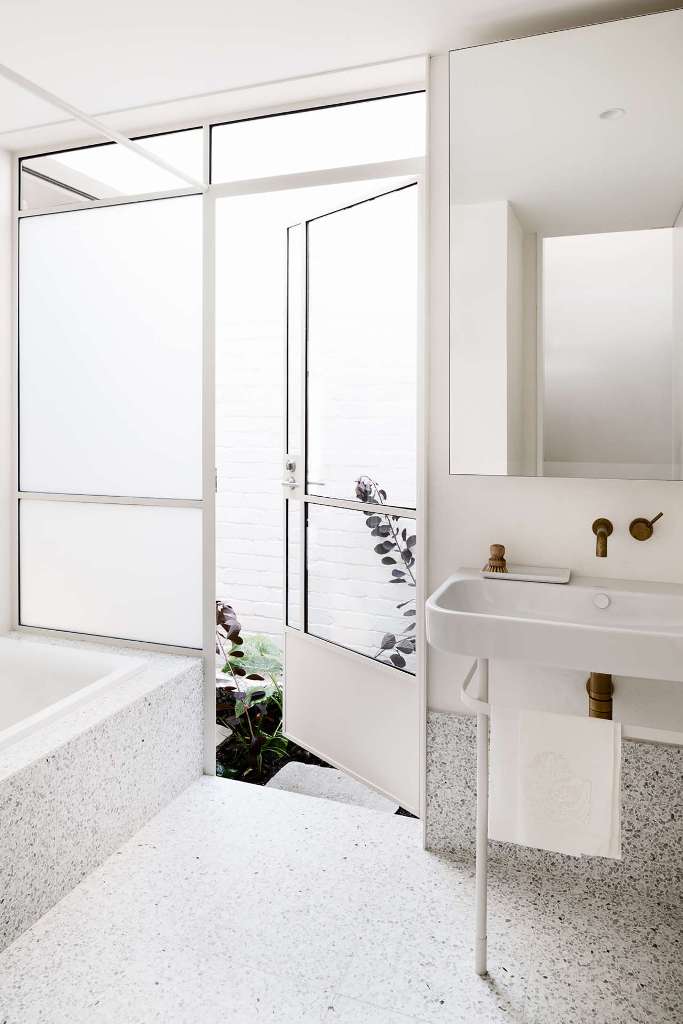The bathroom is done with white terrazzo, with an inner courtyard that allows to connect the space to outdoors