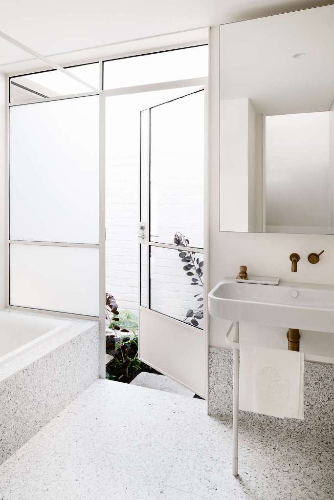 The bathroom is done with white terrazzo, with an inner courtyard that allows to connect the space to outdoors The bathroom is done with white terrazzo, with an inner courtyard that allows to connect the space to outdoors