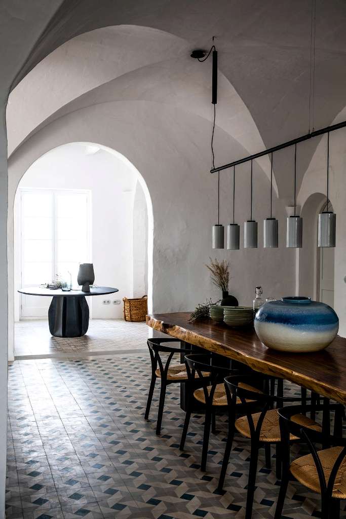 The dining space is done with a wooden table, a range of pendant lamps and a pretty vase, look at the gorgeous tiled floor