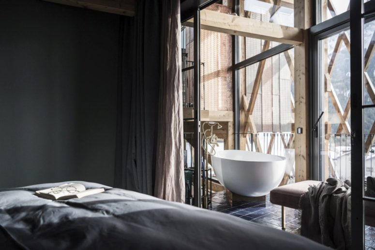 Here's a bedroom that features a bathtub by the window and while taking a bath,the owners can enjoy the views