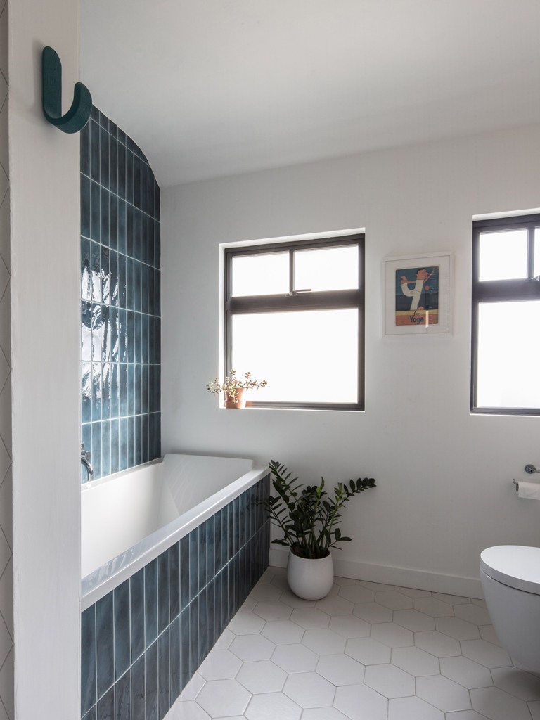 bathroom clad in cool tiles the bathroom is clad with teal tiles on the wall and hexagon ones on the floor and features windows