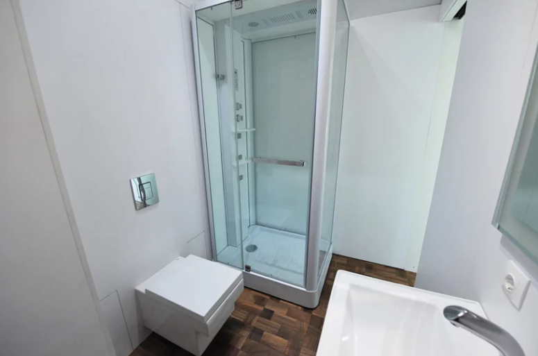 The bathroom is tiny but has everything necessary a shower, a toilet and a sink, it's also done in white The bathroom is tiny but has everything necessary - a shower, a toilet and a sink, it's also done in white