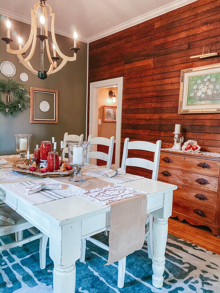 The dining room is done with red wooden planks, a vintage dining set, a wooden chandelier and some artworks