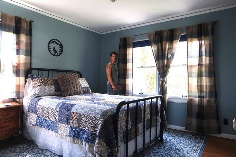 This is a blue guest bedroom with a forged bed, plaid curtains, blue textiles and vintage furniture