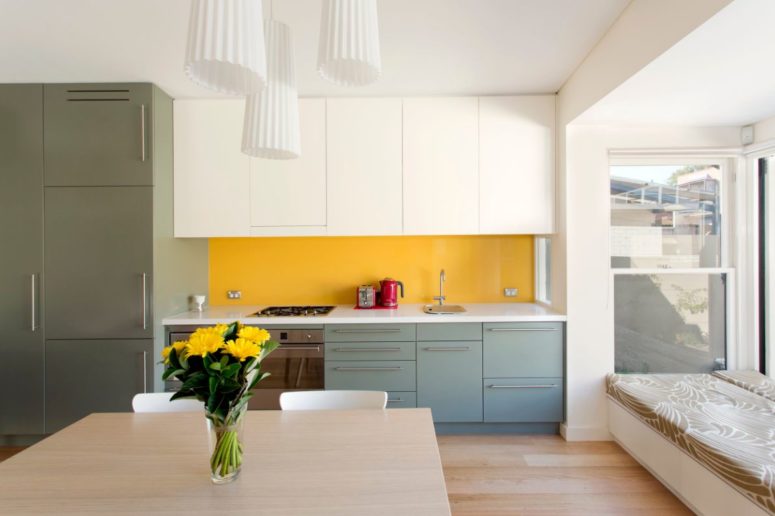 a neutral open space made bolder and brighter with a yellow backsplash, green and grey cabinets