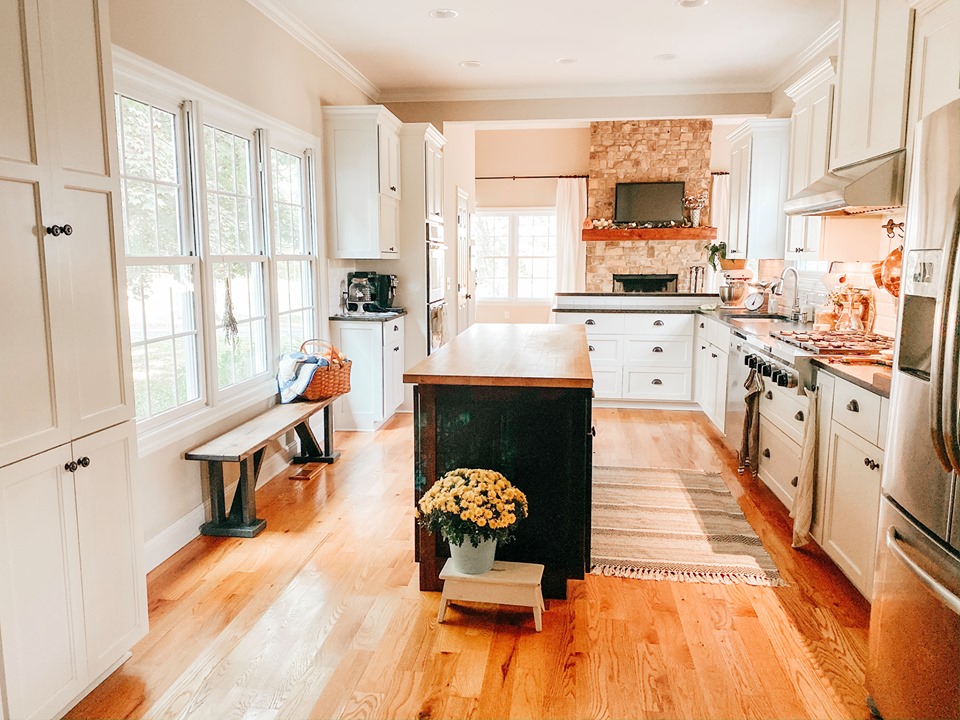 The kitchen is a light filled space, with a brick backsplash, white cabinets and a black kitchen island