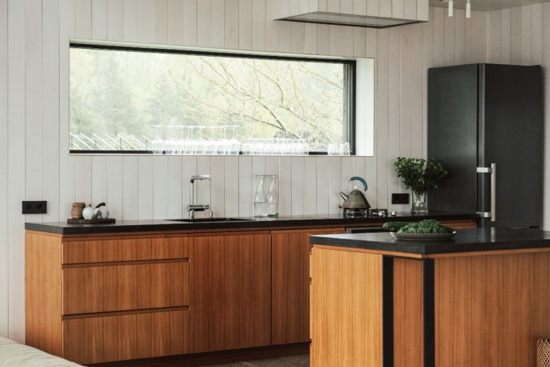 The kitchen is done with white walls, sleek plywood cabinets and black countertops plus a window to enjoy natural light and views The kitchen is done with white walls, sleek plywood cabinets and black countertops plus a window to enjoy natural light and views
