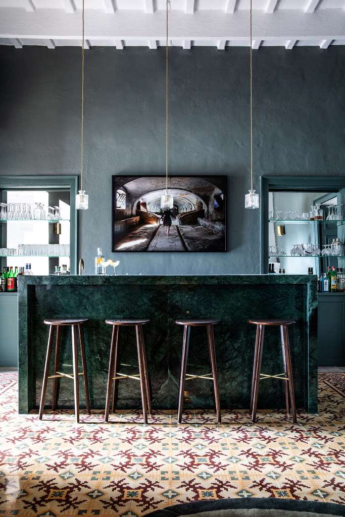 The bar space is done in dark greens, with an elegant marble counter, pendant bottle lamps and built-ins
