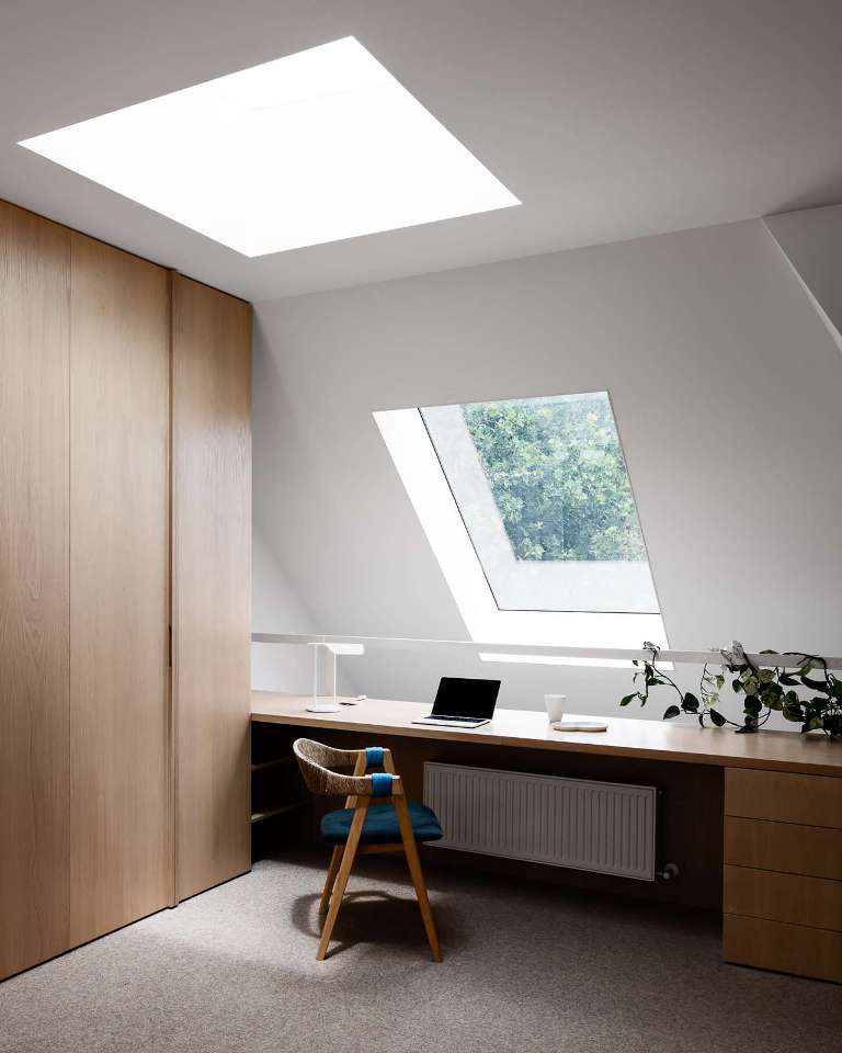 The home office features skylights and attic windows, a sleek storage unit and a large desk