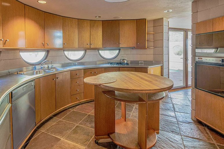 kitchen designed with a lot of wood The kitchen is done with wooden cabinets of various shades coming in an arch and a round kitchen island in the center