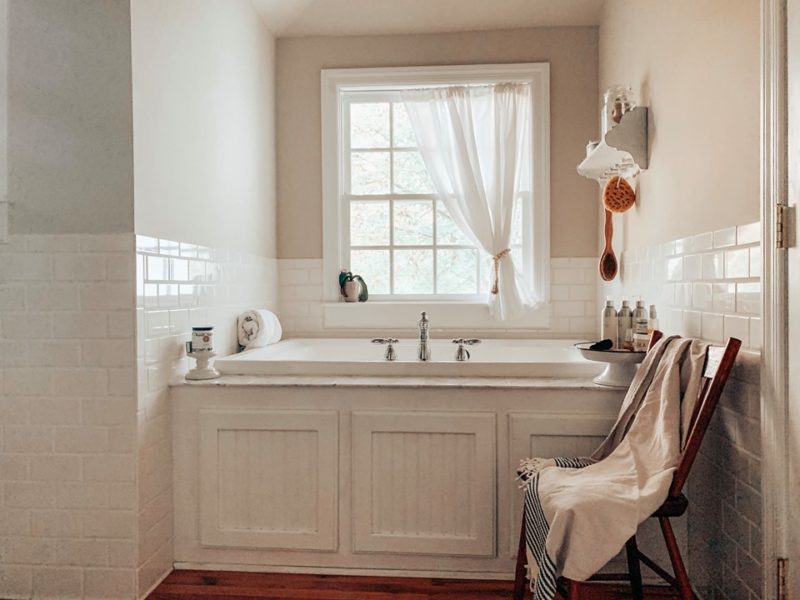 The bathroom is done in white, with a vintage tub and beadboards plus white subway tiles to make it cozy and chic