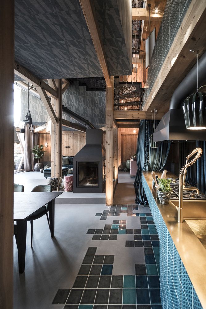 The kitchen flows into a dining space and then into a living room, there's a hearth and curtains that divide the spaces The kitchen flows into a dining space and then into a living room, there's a hearth and curtains that divide the spaces