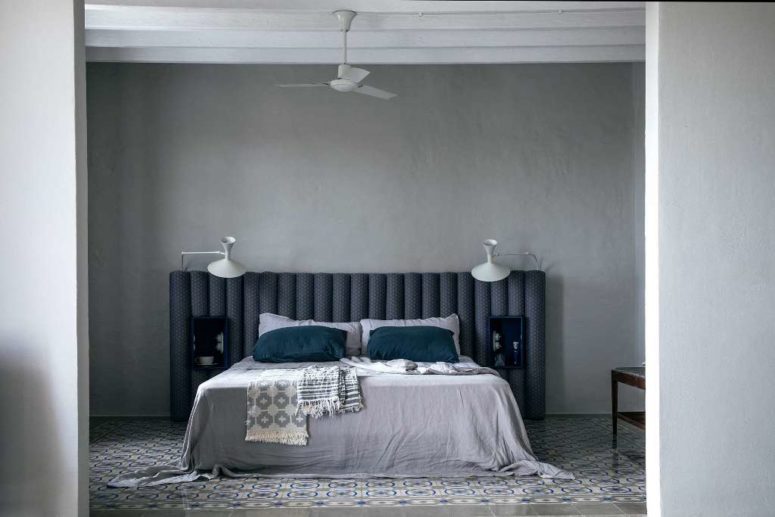 This bedroom is done in grey and teal, with matching tiles on the floor and an upholstered headboard