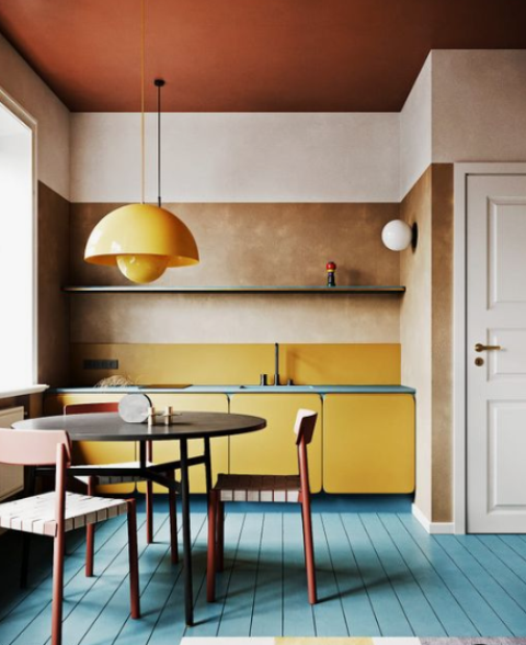 a colorful kitchen done in the shades of yellow, red and blue and calmed down with beige and blush