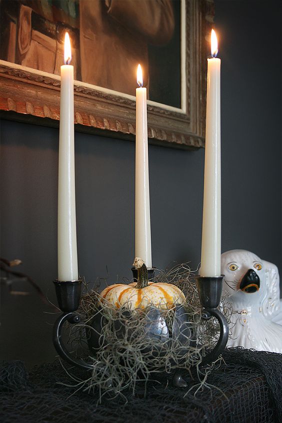 a bowl with hay, a pumpkin and three candleholders in black is a stylish and scary idea for Halloween