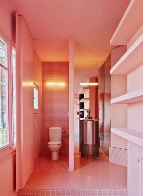 a whimsy bathroom done in salmon pink, with built-in shelves and windows to floof the space with natural light