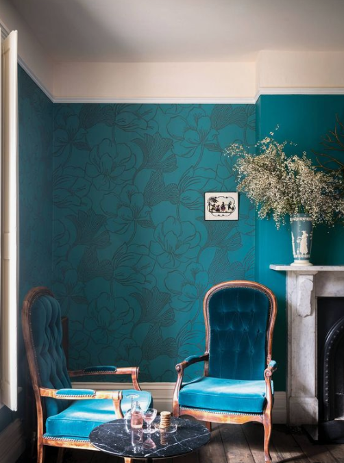 a refined living room done in bold shades of blue, with elegant furniture, a marble fireplace and a coffee table