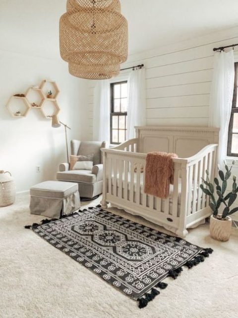 a boho meets vintage nursery with a wicker lampshade, hex shelves, a boho rug, grey furniture