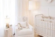 a neutral baby nursery with a jute rug, a white Moroccan pouf, a tree stump, a perforated lamp and a vintage crib