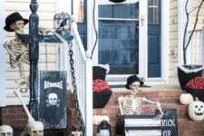 a skeleton porch with several skeletons, skulls, skeleton hands, a black wreath, a sign and spiderwebs looks impressive