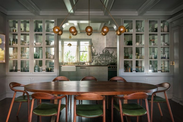 The kitchen and dining space are divided with large storage units and the green chairs add color