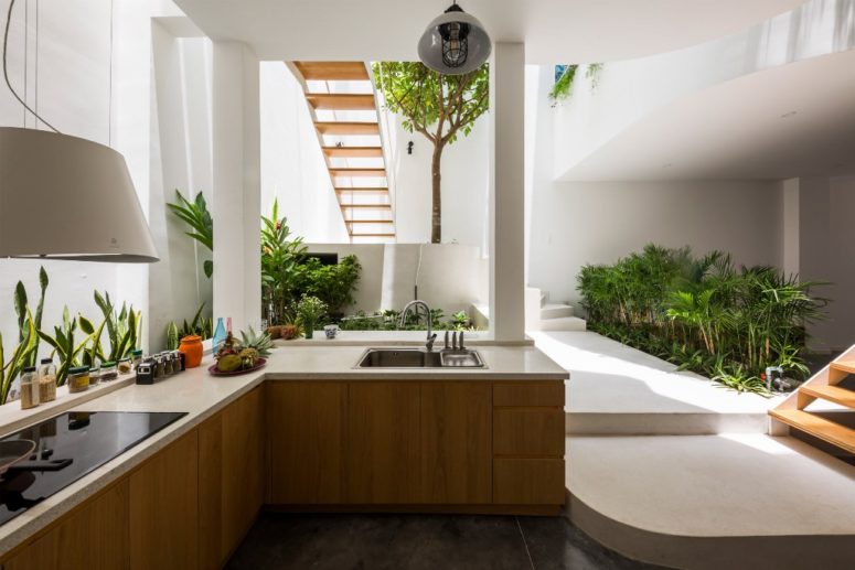 The kitchen is done with sleek cabinets, white stone countertops and greenery all along