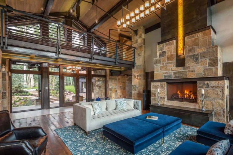 The living room is done with a large stone fireplace, navy and grey furniture with timeless elegance