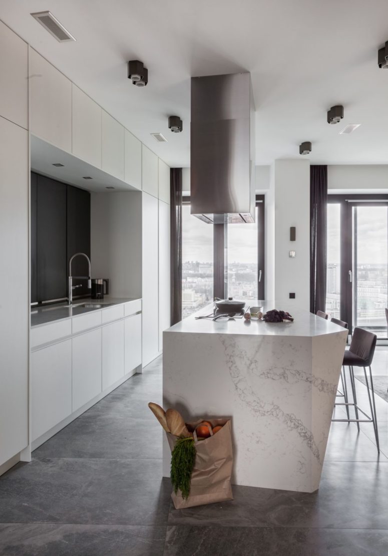 an airy all white kitchen design The kitchen is all-white with a marble kitchen island and a glazed wall fills the space with natural light