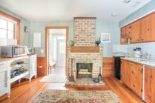 05 The kitchen is done with rich stained cabinets, light blue walls and backsplashes, a fireplace that is working