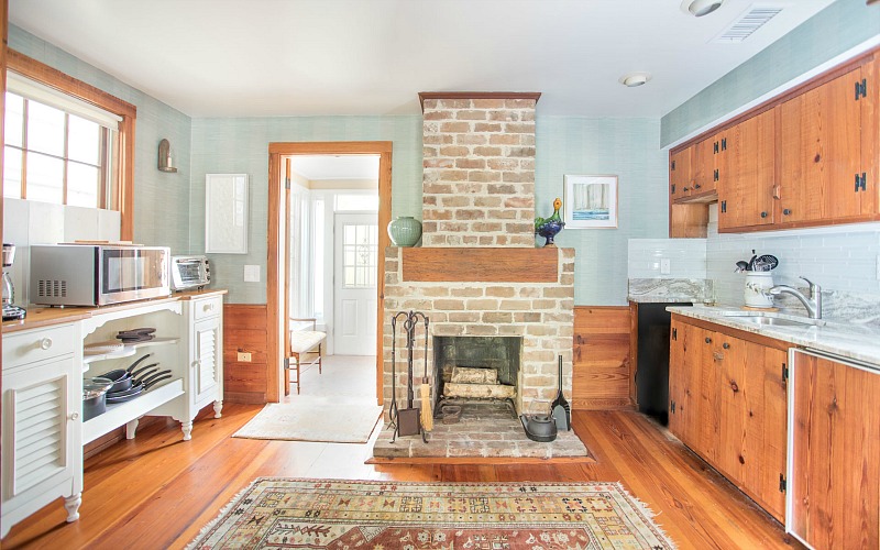The kitchen is done with rich stained cabinets, light blue walls and backsplashes, a fireplace that is working