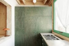05 The kitchen is done with tiles and dark green plywood cabinets and a large kitchen island
