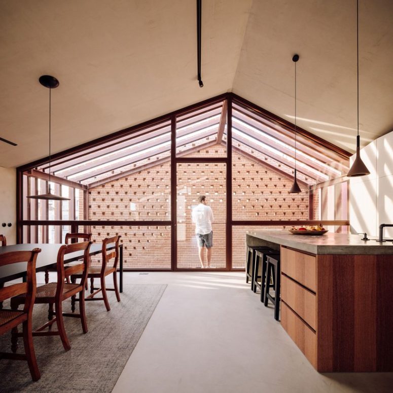 a cozy kitchen design with a wooden island The kitchen is done with white cabinets and a wooden kitchen island with a concrete countertop, and here there's a cozy dining space with refined chairs