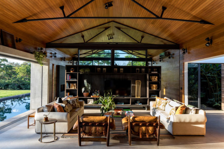 The living room is done with comfortable and stylish furniture, with a shelving unit and greenery in pots The living room is done with comfortable and stylish furniture, with a shelving unit and greenery in pots