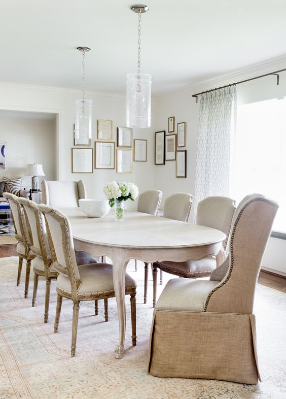 a chic and elegant neutral dining room with upholstered furniture, cool glass pendant lamps and a vintage table