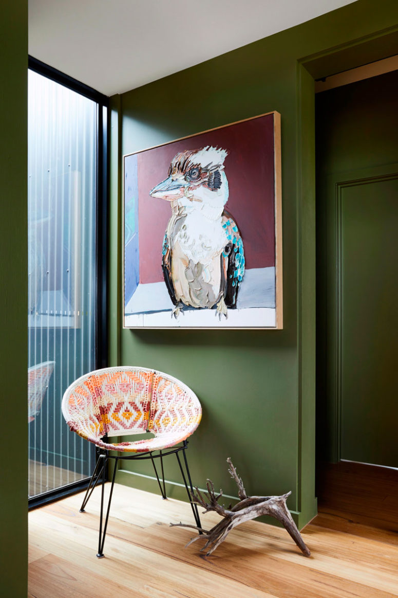 Green used for walls is rather muted to make the space feel more like nature, there's a colorful chair and a bold statement artwork Green used for walls is rather muted to make the space feel more like nature, there's a colorful chair and a bold statement artwork
