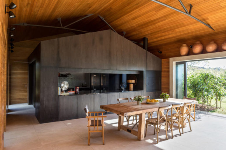 The kitchen is done as a darkened wood cube, and oppposite it there's a dining space with light furniture The kitchen is done as a darkened wood cube, and oppposite it there's a dining space with light furniture