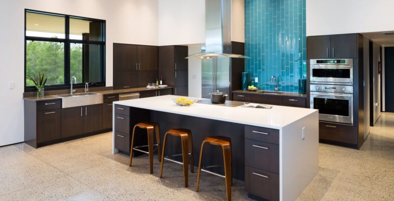 The kitchen is done with dark furniture, white countertops and a blue tile backsplash