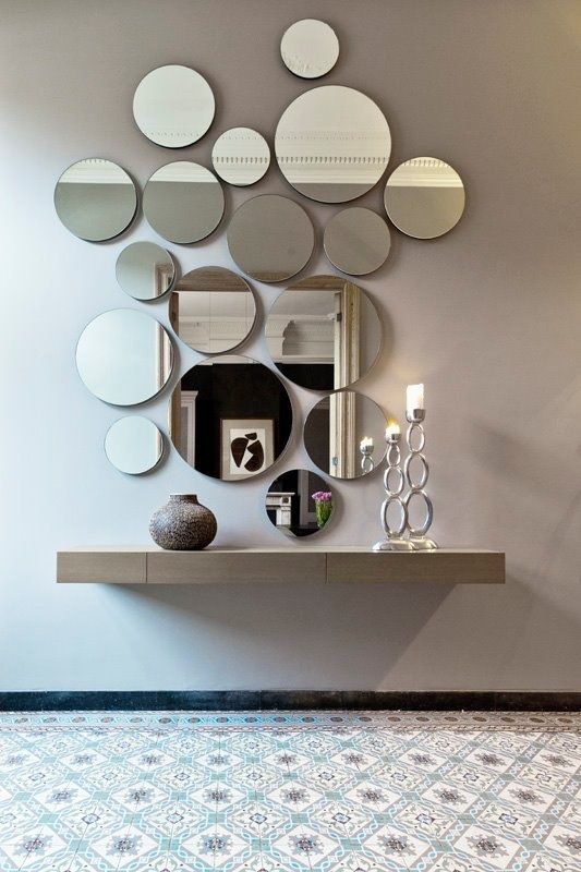 an arrangement of round mirrors of various sizes and a floating vanity for an ethereal look