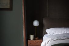 07 The bedroom is dark and welcoming, with an upholstered bed and an oversized headboard