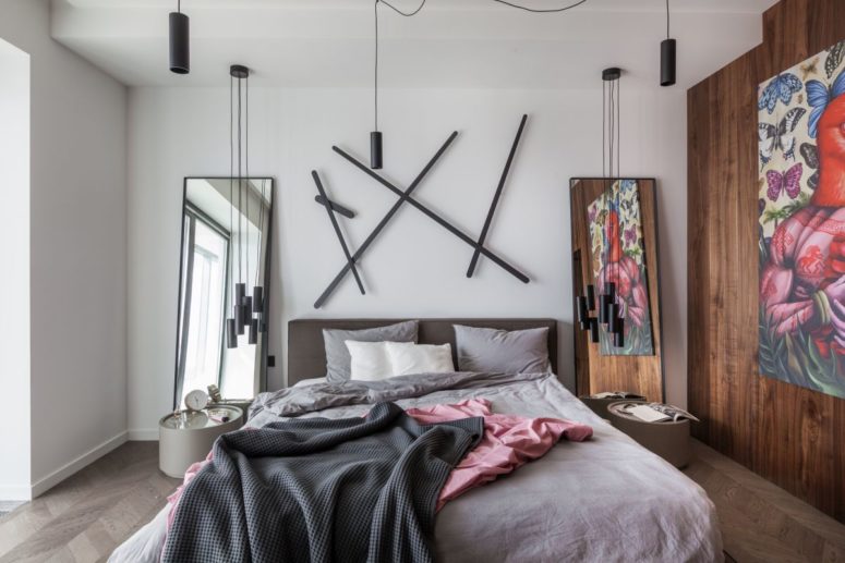 The bedroom is modern and whimsy, wih a bed, a creative artwork, pendant lamps, mini nightstands and a mirror The bedroom is modern and whimsy, wih a bed, a creative artwork, pendant lamps, mini nightstands and a mirror