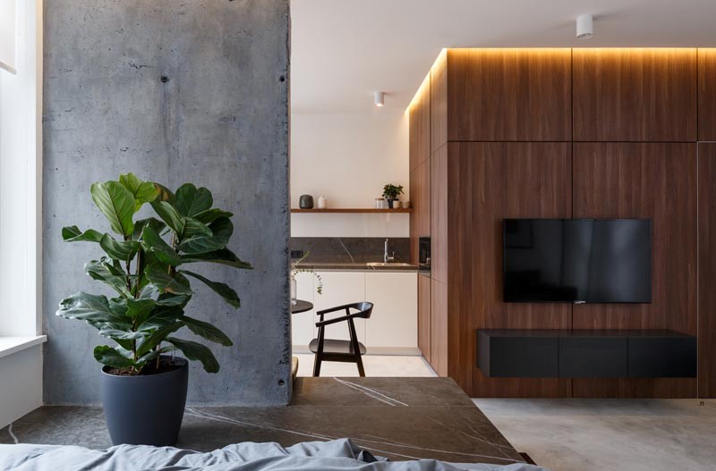 The wood clad wall features a floatign cabinet and a TV