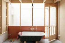 a black free-standing bathtub looks nice against light wood background