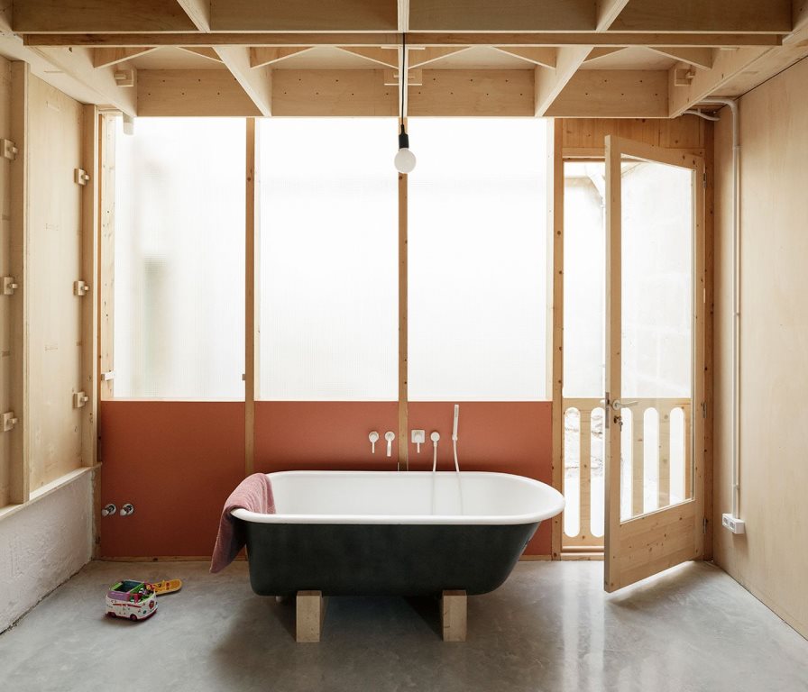 a black free standing bathtub looks nice against light wood background